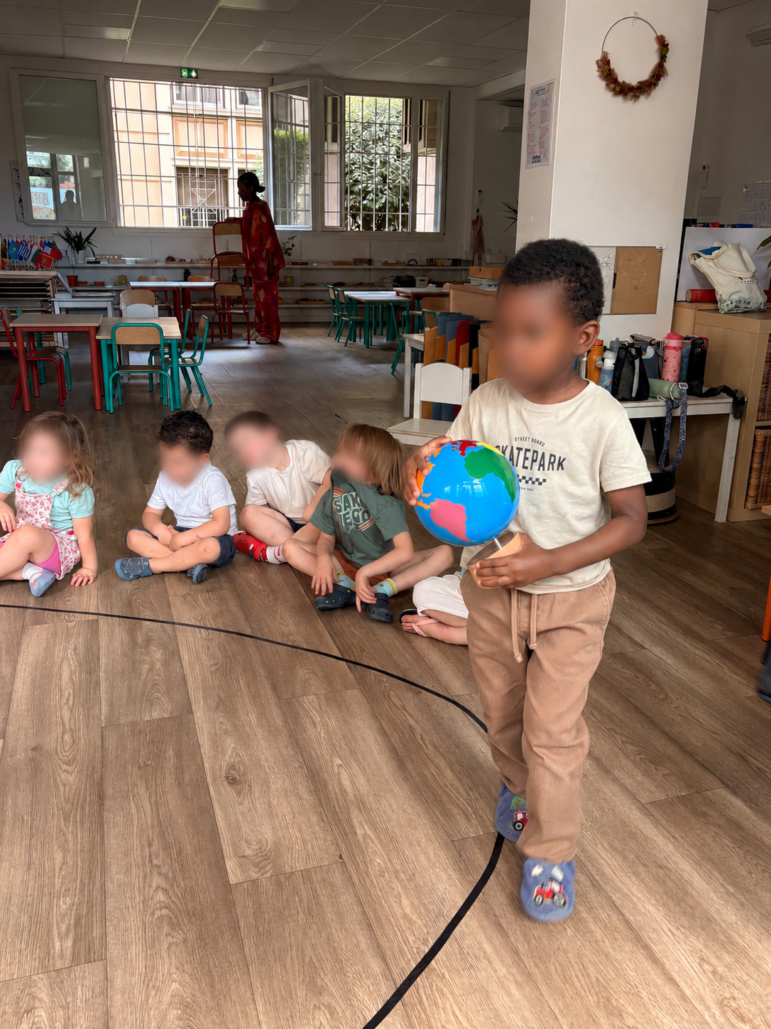Un enfant porte le globe autour du cercle pendant le rituel de l'anniversaire, les autres enfants assis au sol