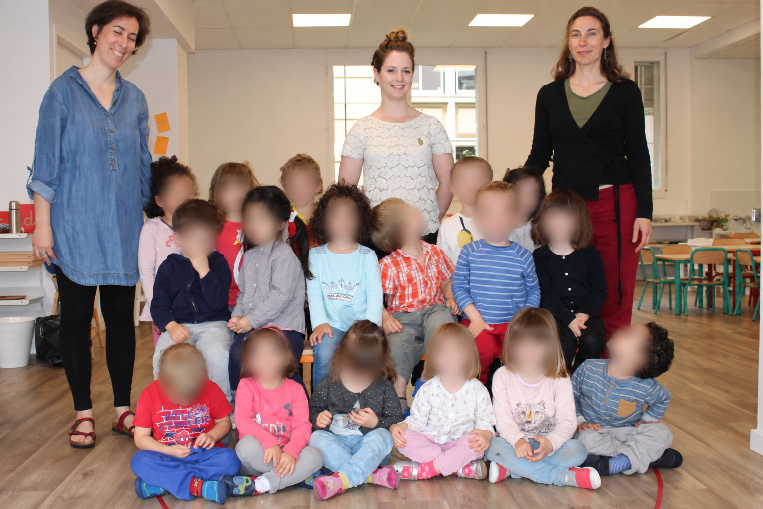 Photo d'archives : les enfants des premières années de l'école posent avec les trois adultes de l'équipe dans la classe