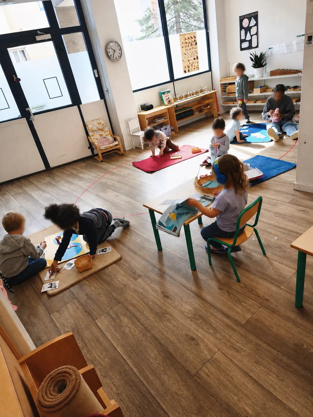 Vue d'ensemble de la classe lumineuse : des enfants travaillent au sol sur des tapis et à de petites tables