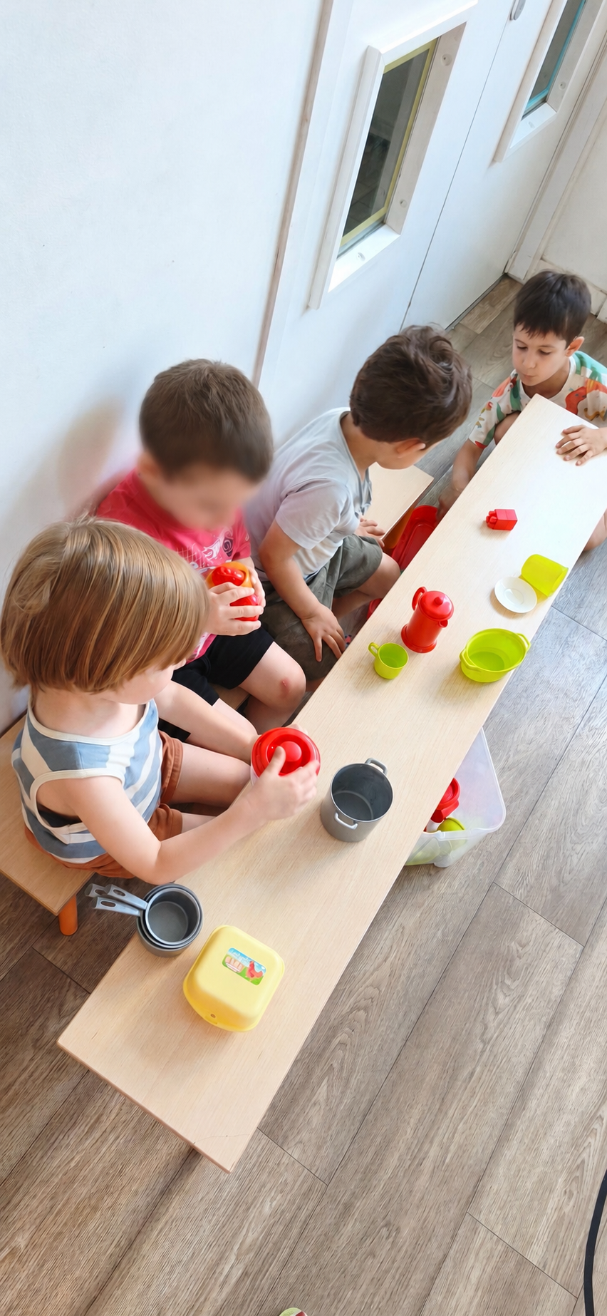 Des enfants jouent ensemble à la dînette autour d'une petite table pendant la garderie