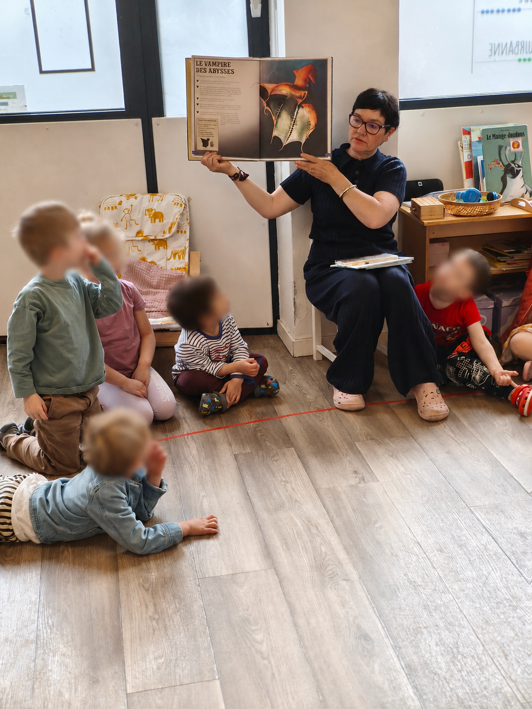 Corinne lit un album à un petit groupe d'enfants dans la classe.