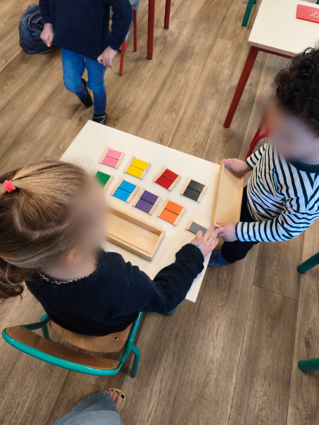 Deux enfants partagent une activité dans la classe Montessori.