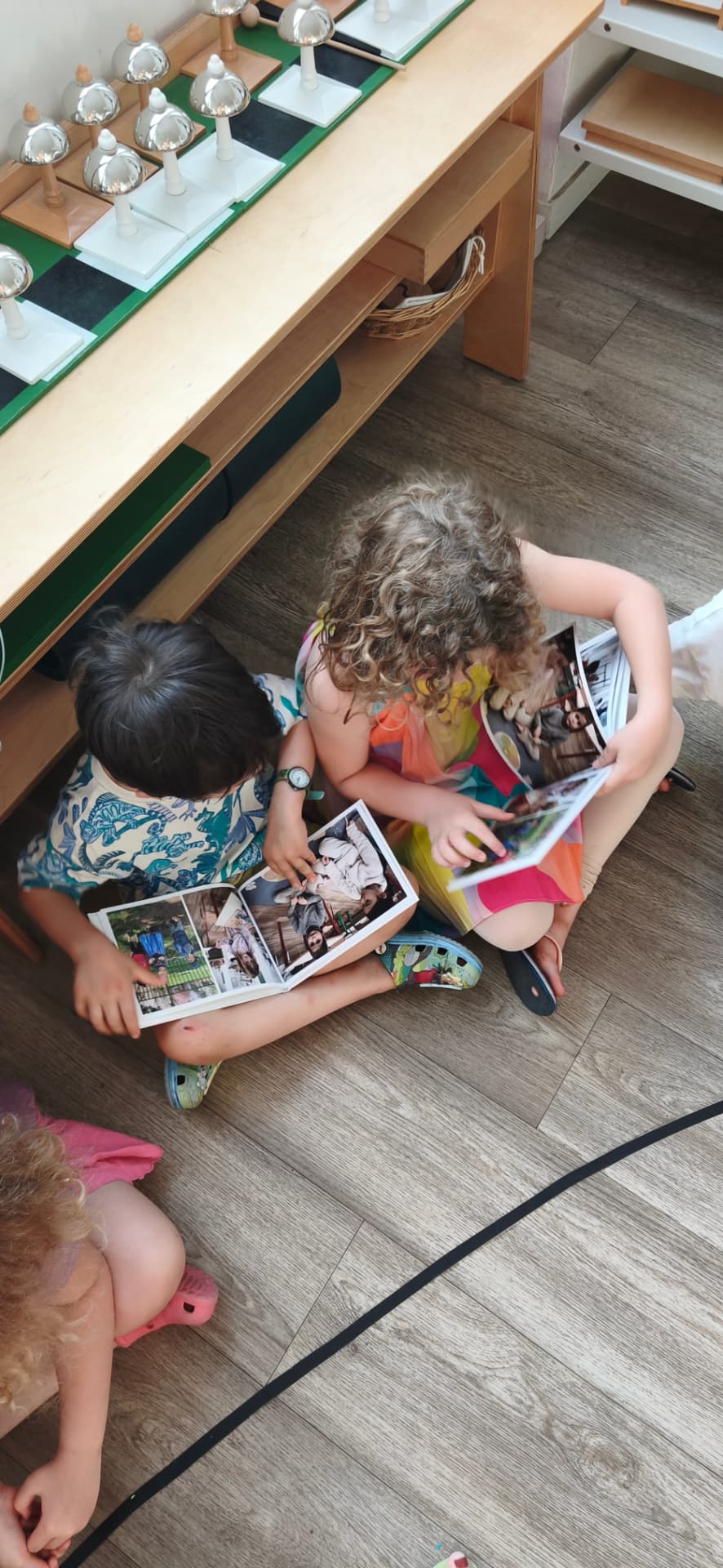 Deux enfants assis au sol feuillettent ensemble les albums photos de l'école