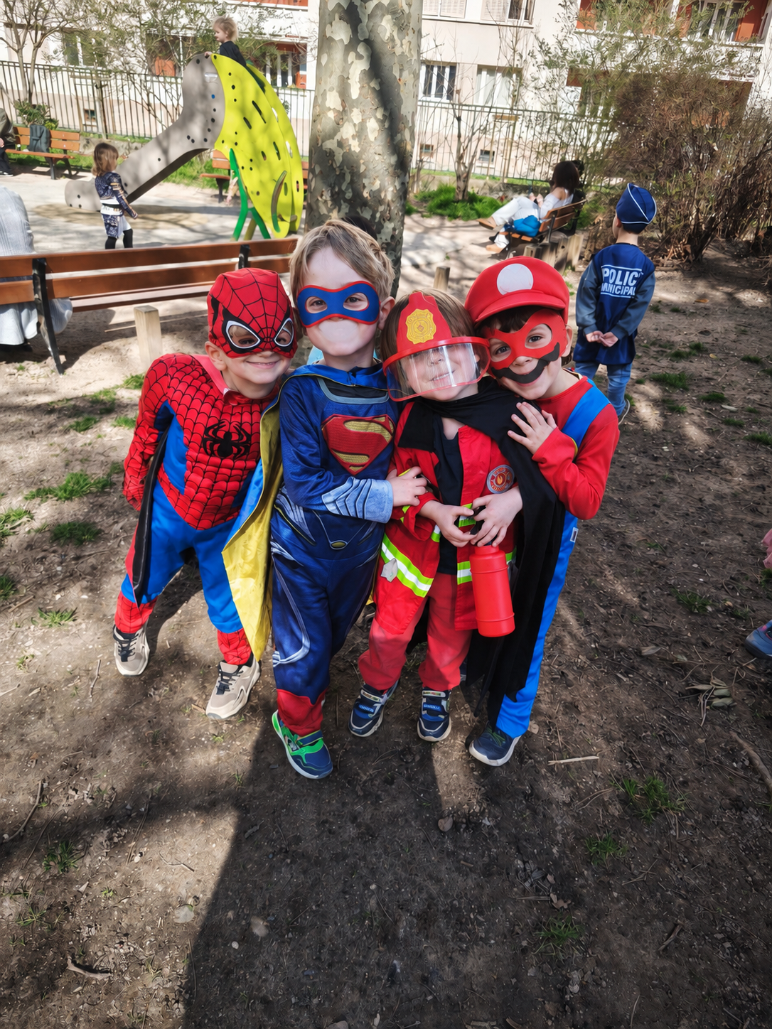 Quatre enfants déguisés en super-héros posent ensemble dans le square lors du carnaval de l'école